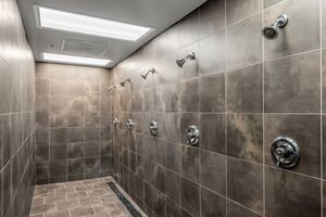 Luxury multi-head shower room with large gray marble-style tiles, chrome fixtures, and a skylight above.
