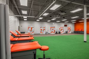 Athletic training room with orange padded tables, green turf flooring, and UTRGV lettering on white walls.