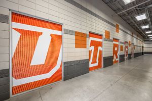 Stadium interior hallway featuring bold orange and white UTR letter graphics on walls.