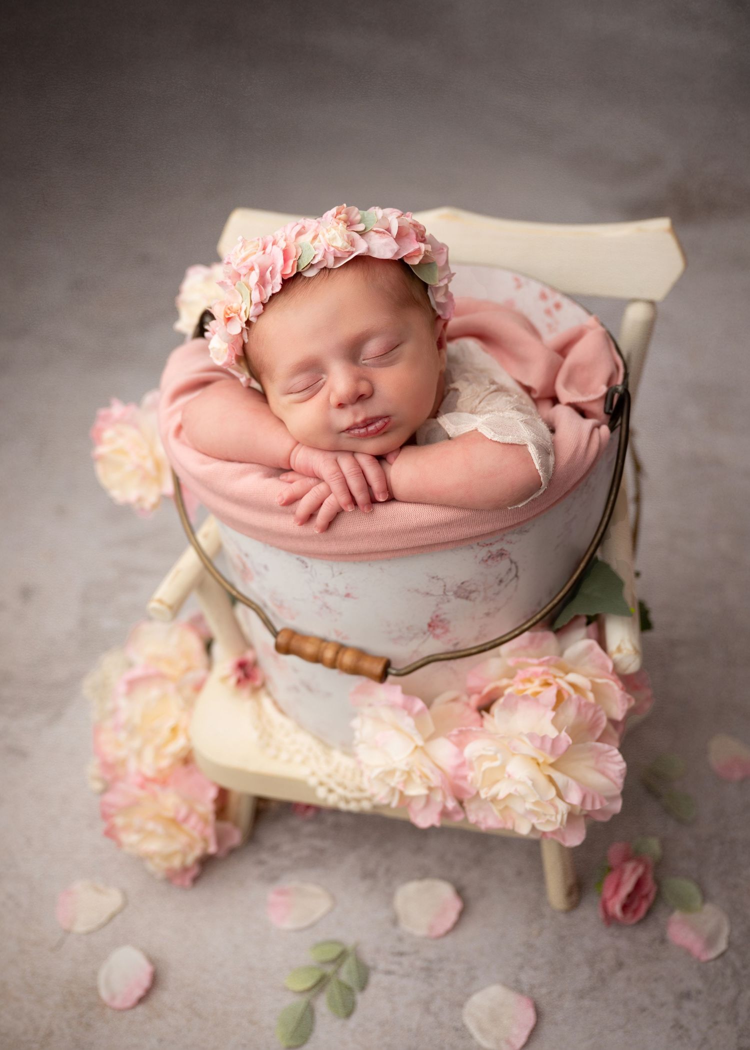 Newborn baby girl posed in a floral prop during a studio newborn photography session