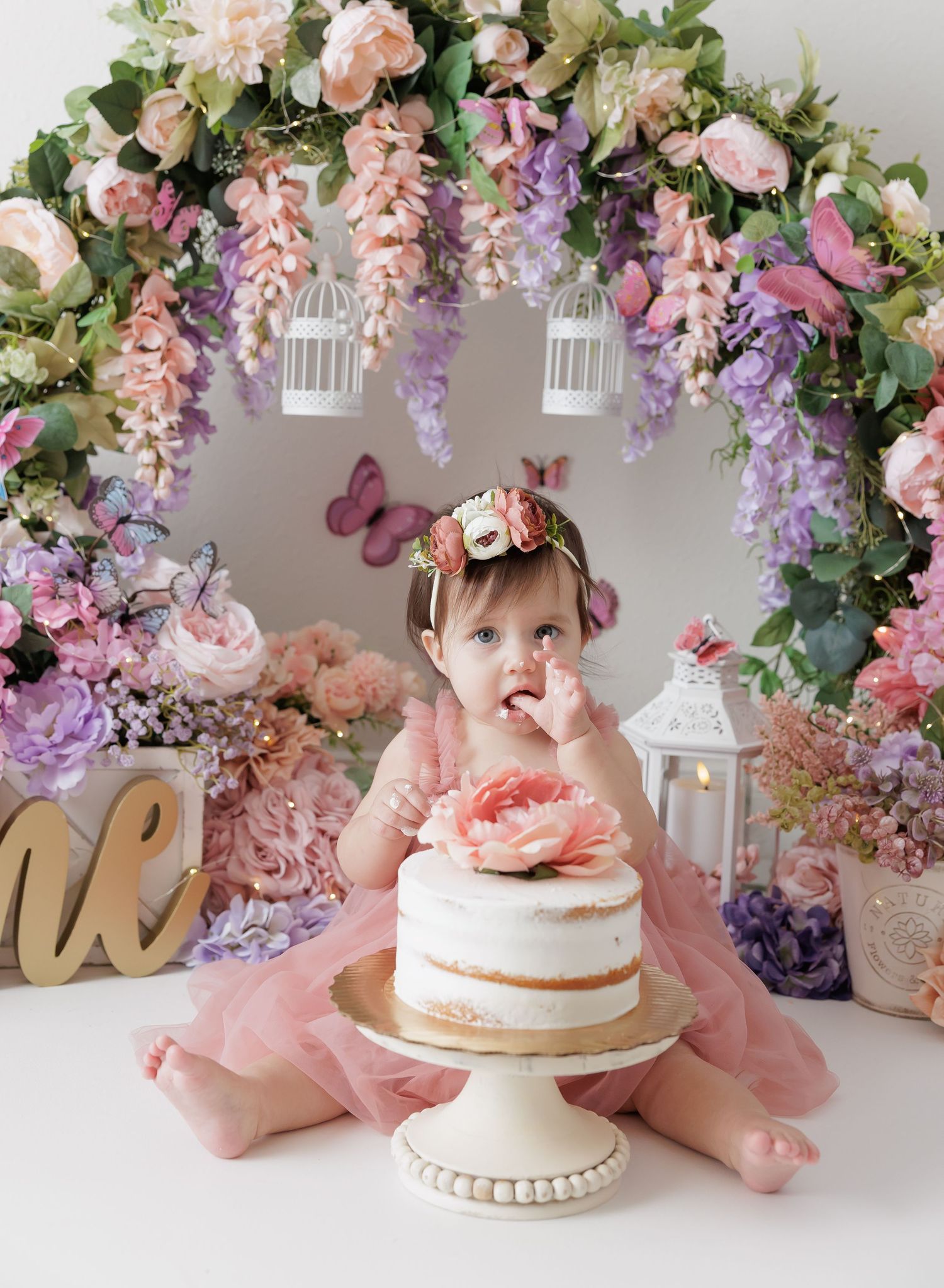 Elegant peach dress photoshoot with gold balloons and garland against white backdrop.