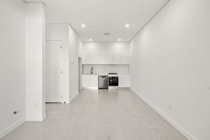 Compact studio space with white cabinetry kitchenette, stainless steel appliances, and polished concrete flooring.