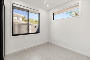 Small empty room with high black-framed clerestory window, white walls, and light grey tile flooring.