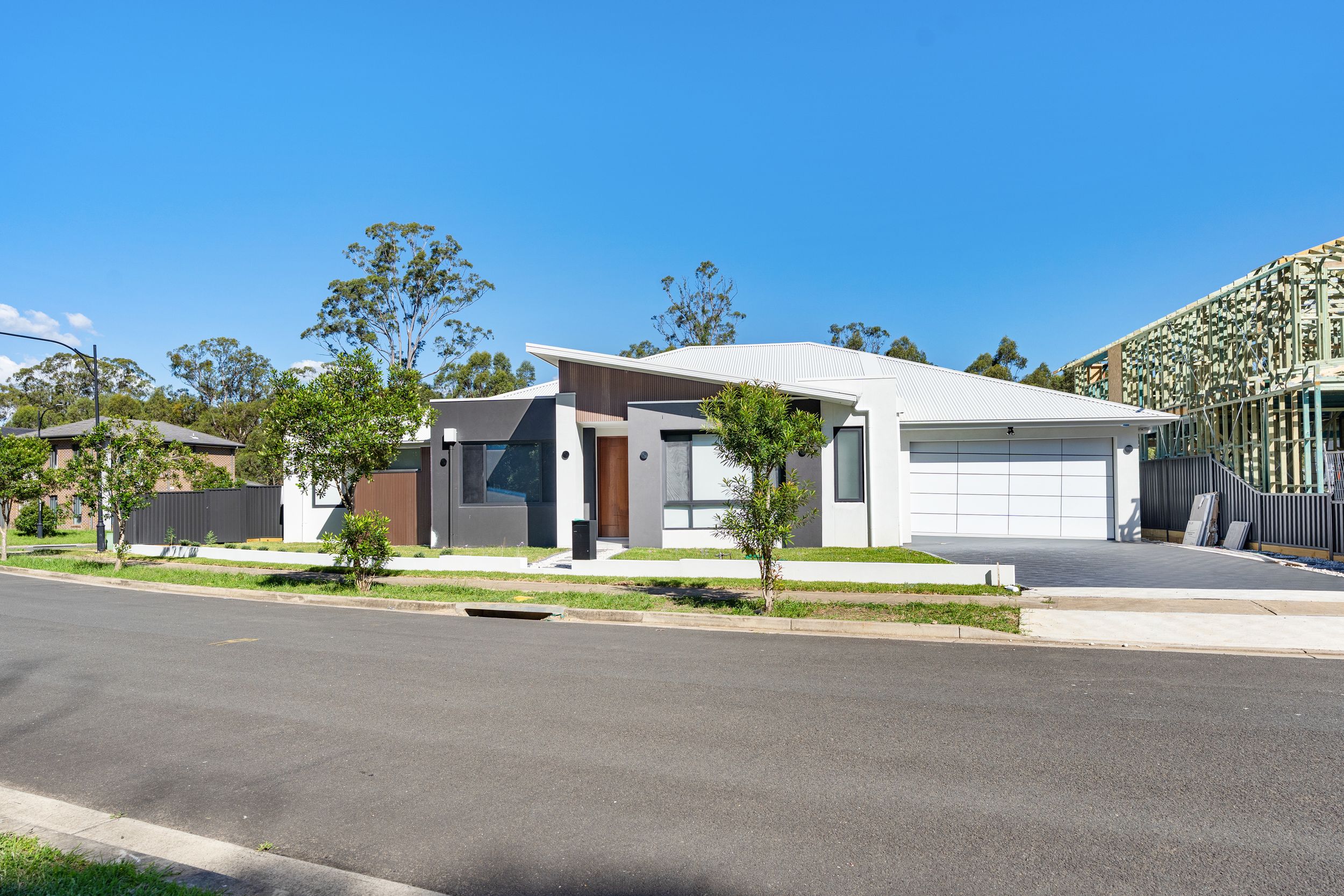 Modern single-story home with white render, dark timber entry, double garage, and manicured front lawn on quiet street.