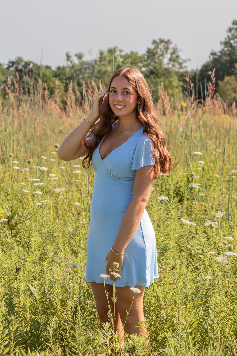 A girl in a blue dress posing for her senior photo in a field in Strongsville.