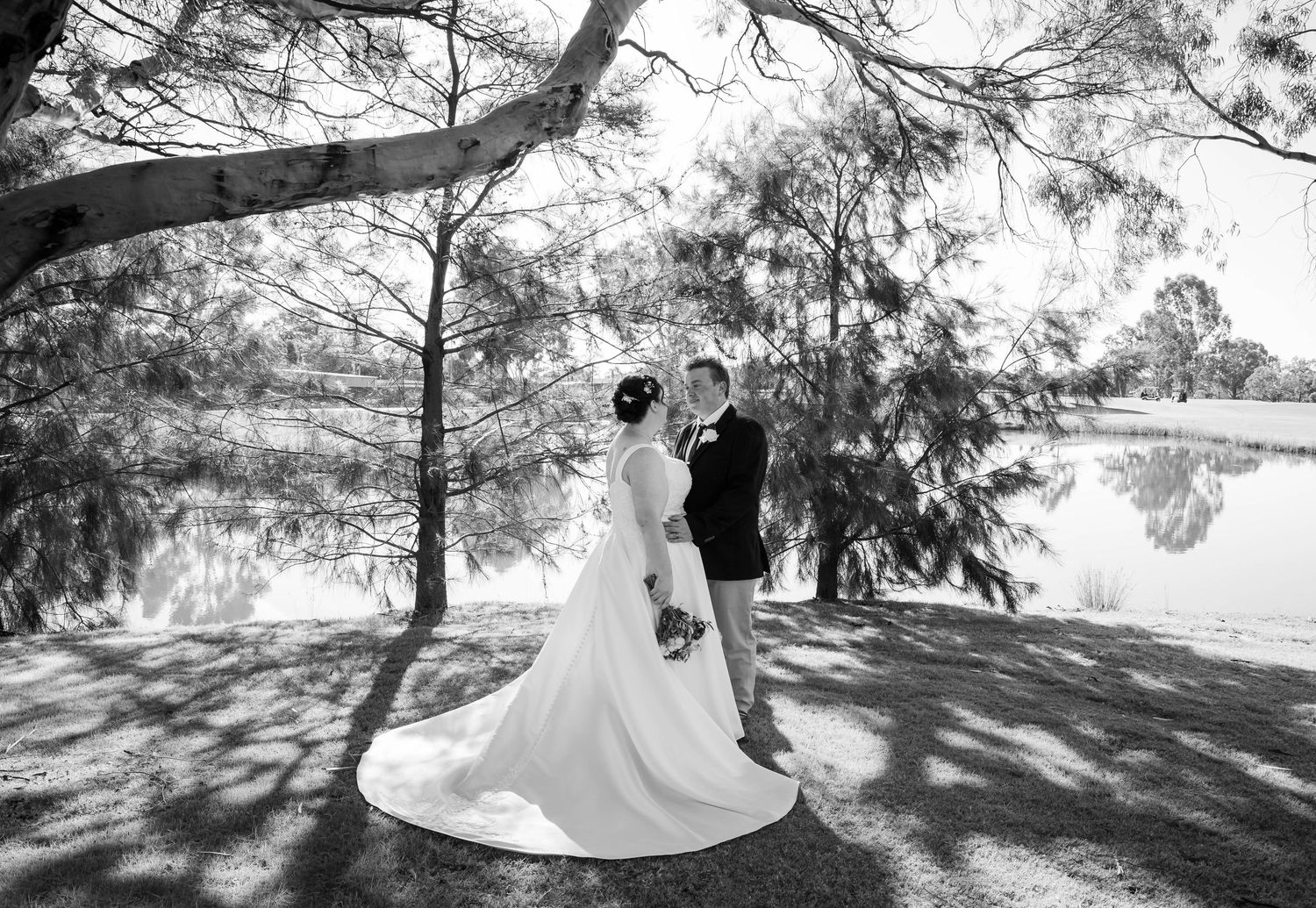 Black and white photo of a bride and groom sitting on a vintage sofa outdoors with ribbon backdrop.