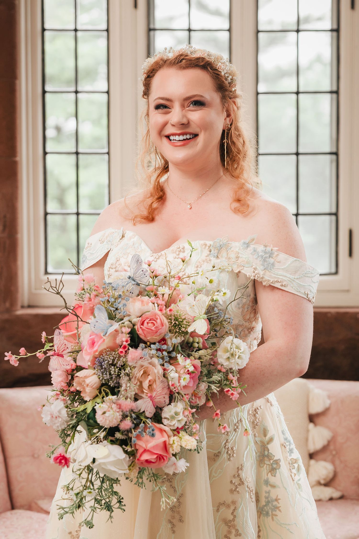 Bride smiling with her pink and white bouquet in front of arched windows at Searles Castle.