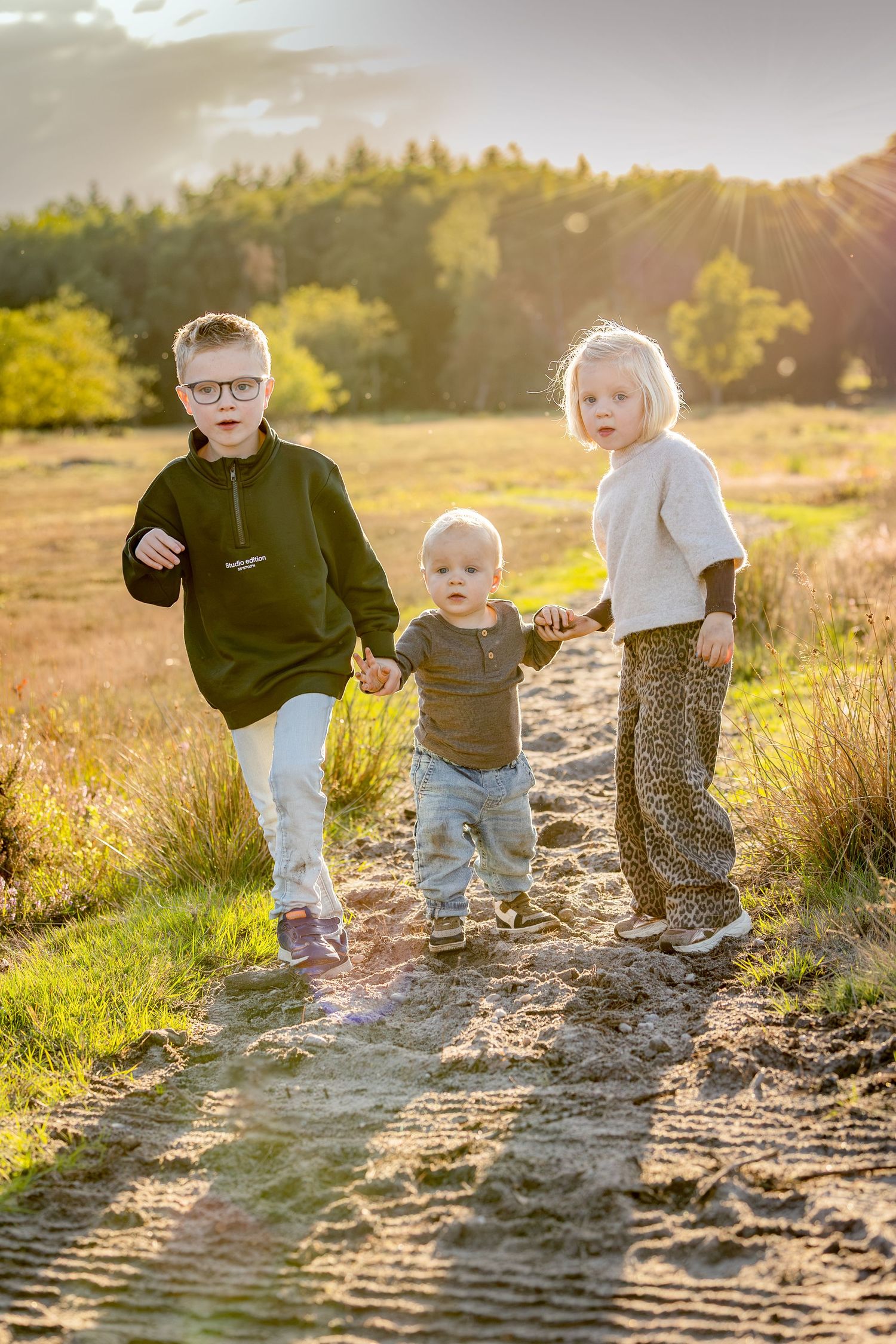 gezinsfoto waarbij papa en mama allebei een dochter optillen en dicht tegen elkaar aan staan