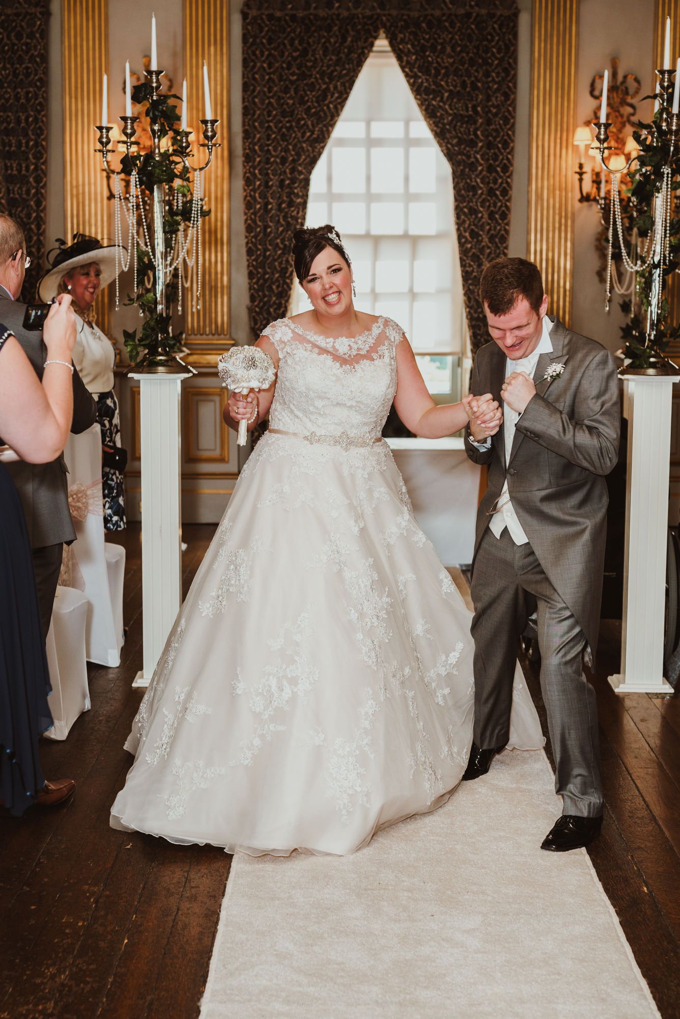 Bride and groom walk joyfully down the aisle after wedding ceremony in elegant decorated venue.