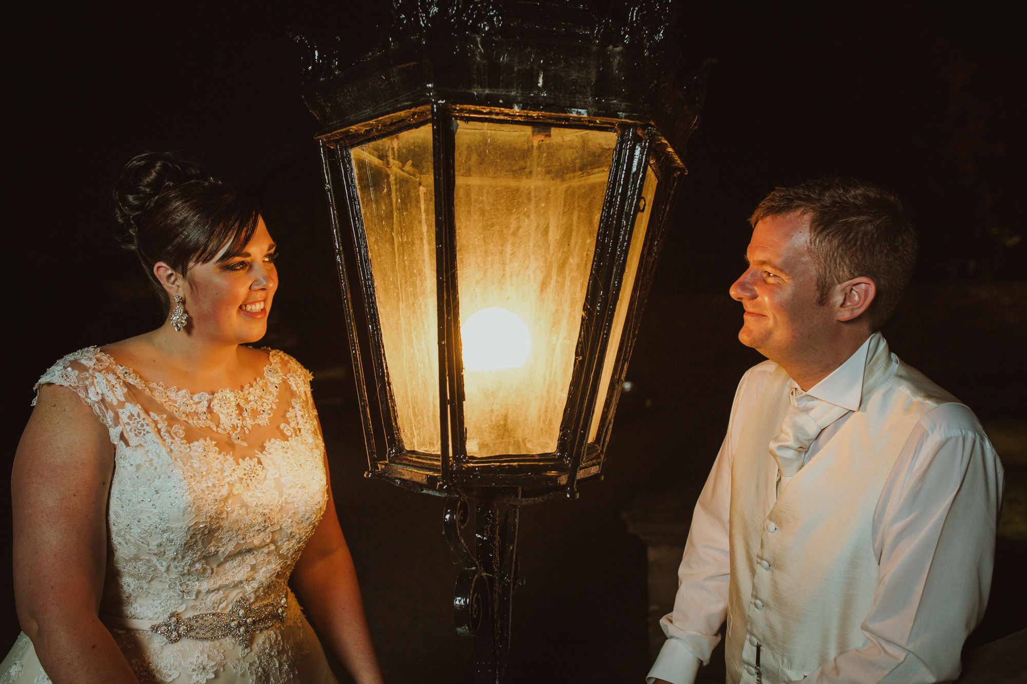 Nicola and Ashley beside an illuminated lantern at Knowsley Hall after dark