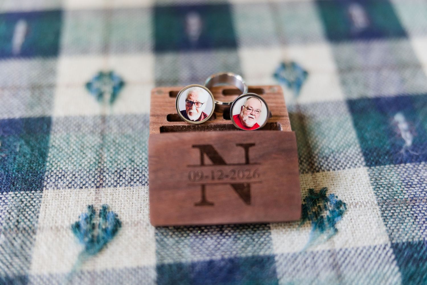 Custom photo cufflinks with portraits displayed on a engraved wooden monogram box with date on plaid fabric.