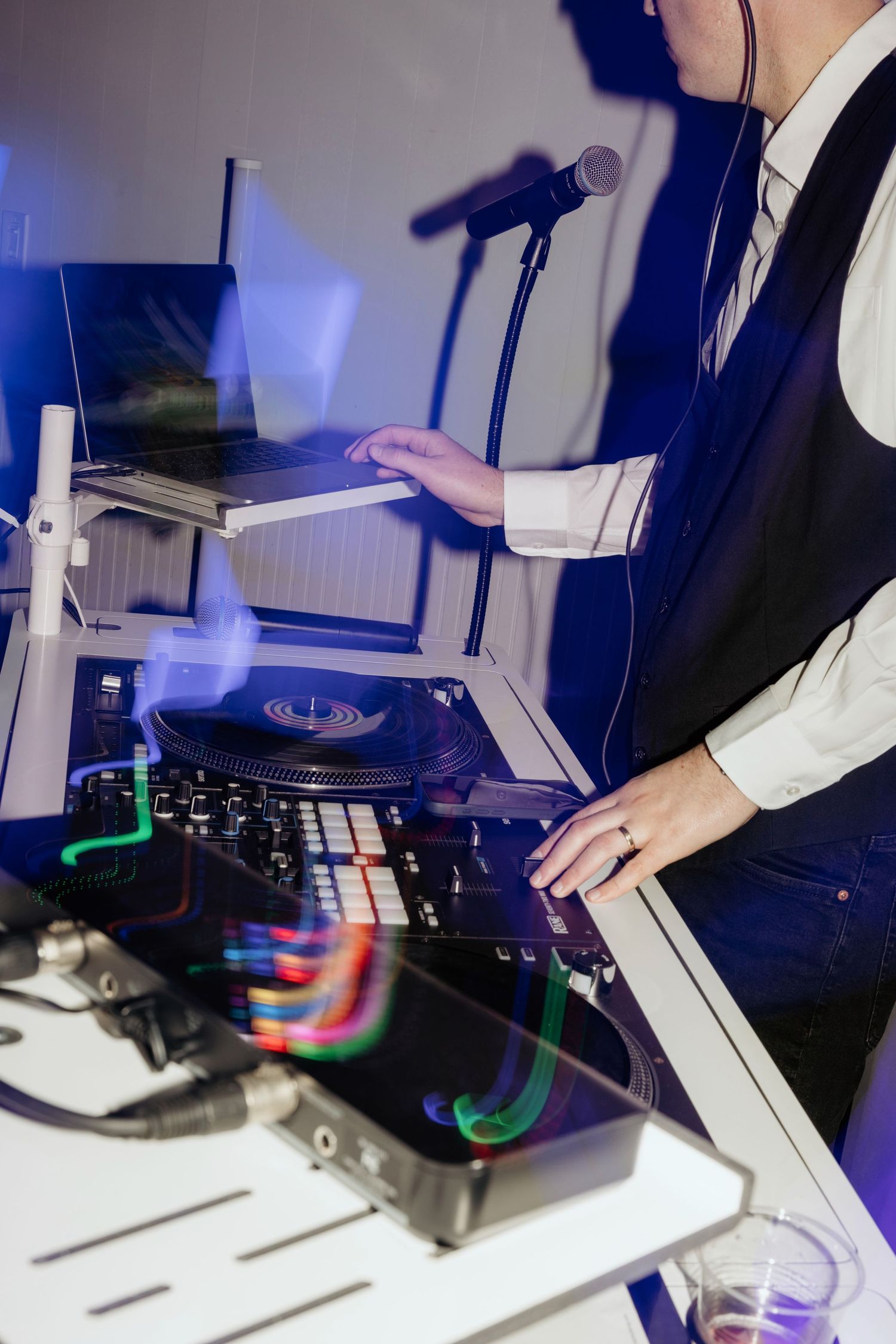 DJ mixing music at a professional turntable setup with colorful LED lights and laptop at a wedding in Greensboro, Georgia.