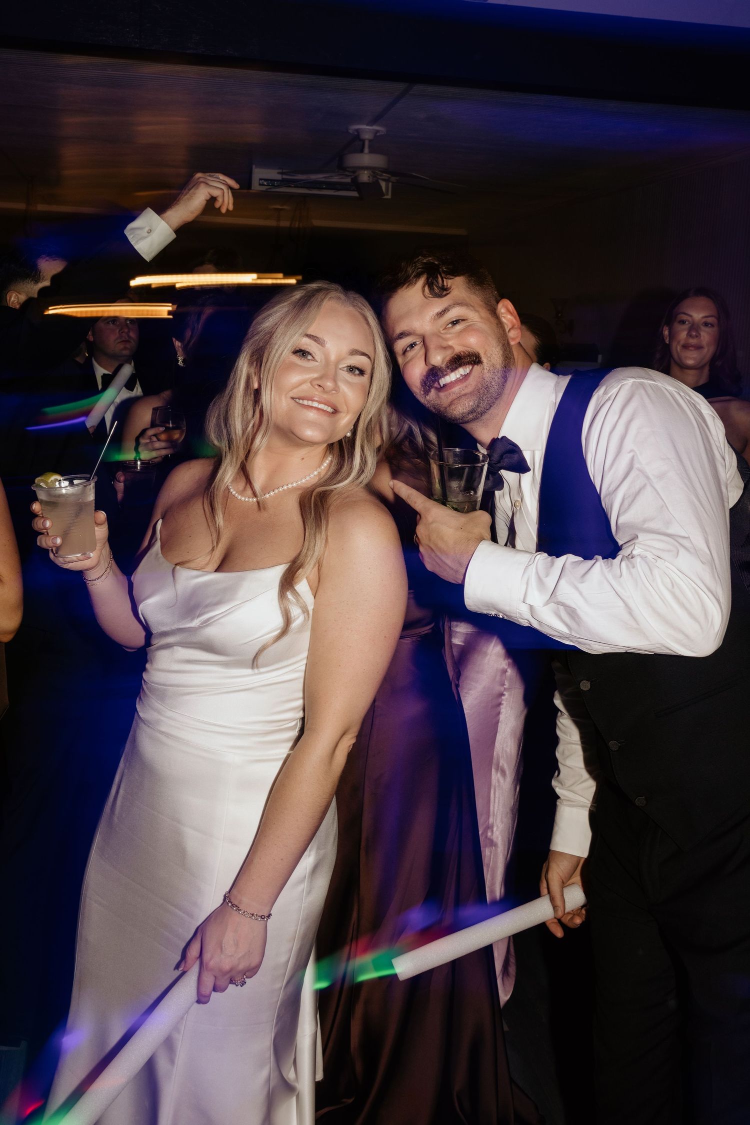 Bride and groom smiling together on the dance floor at their wedding reception in Georgia with colorful glow sticks.