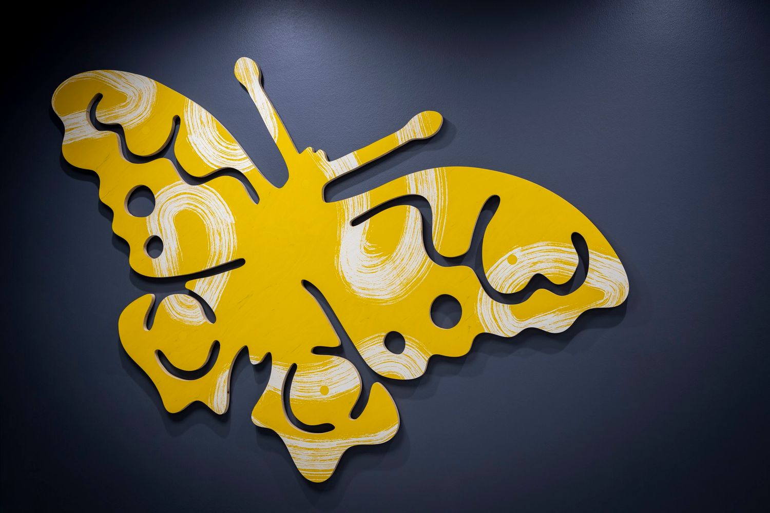 Yellow butterfly metal wall art decoration with black outline details on a dark gray background.