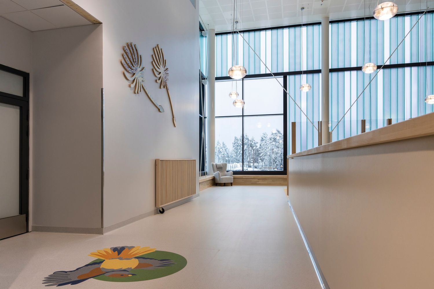 Modern school hallway with floral wall art, colorful floor rug, and large windows flooding the space with natural light.