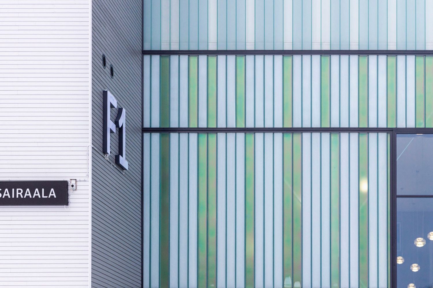 Close-up of modern hospital building facade featuring colorful vertical green and white glass panels.