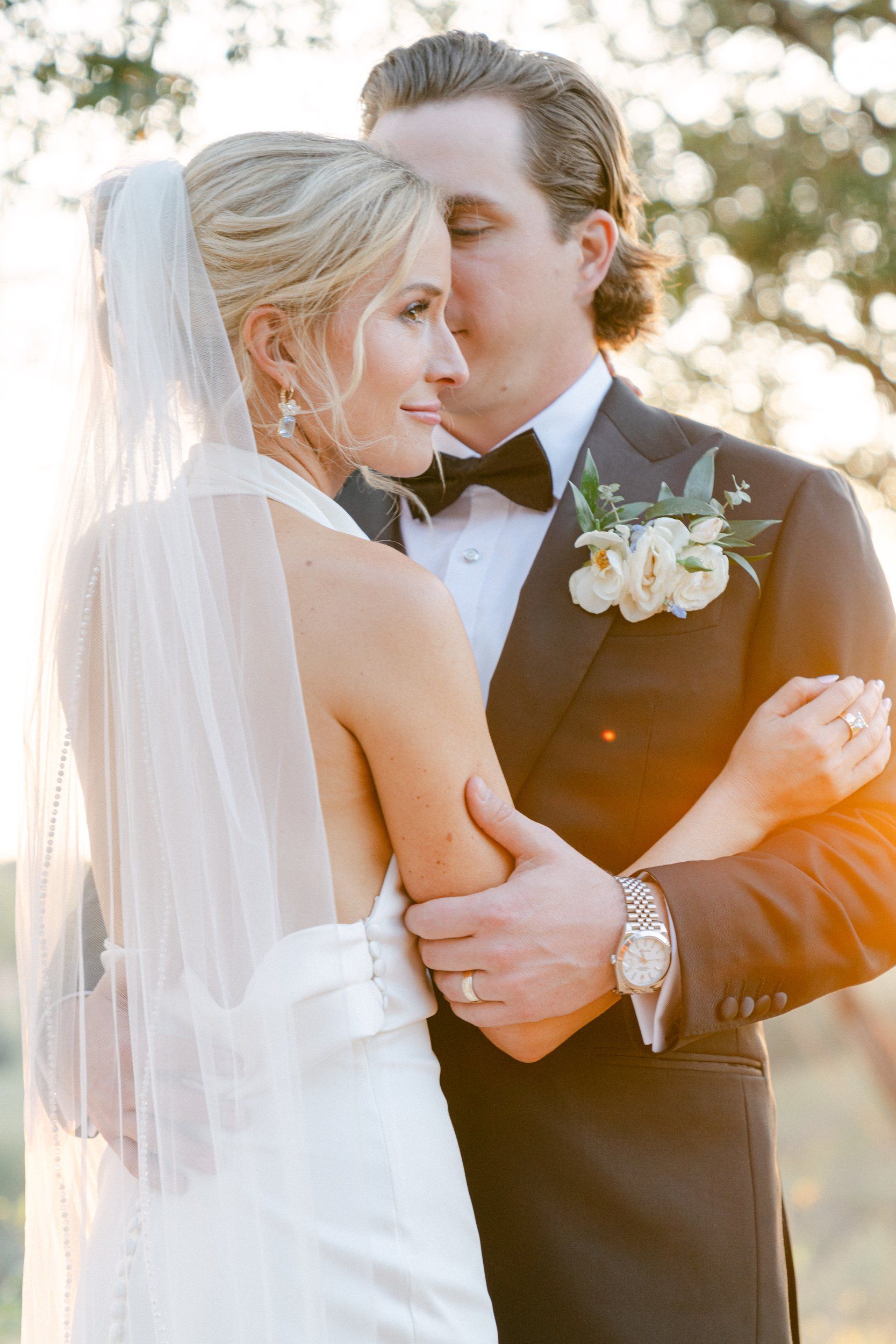A bride with a cathedral veil held close by her groom in golden Hill Country light, photographed by Annie Strever, Austin wedding photographer