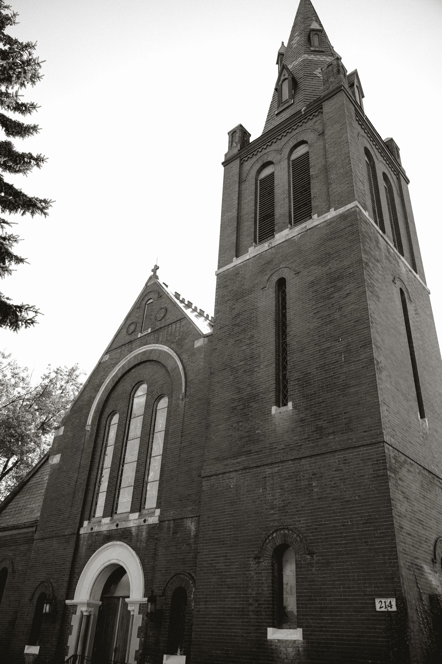 Black and white view of a historic brick church with a tall bell tower and arched windows.