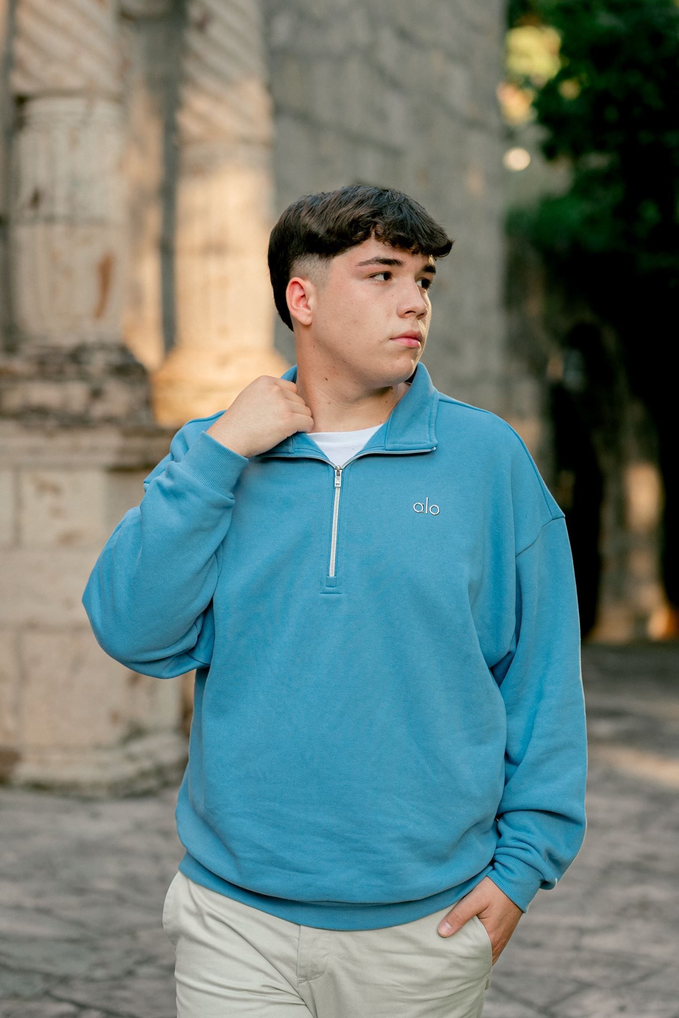 High school senior wearing blue Alo top and khaki pants.