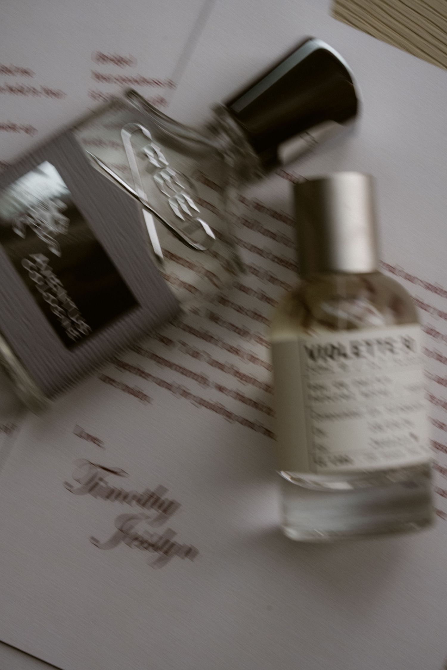 Two luxury perfume bottles resting on a wedding stationery card personalized with the names Timothy and Jesslyn.