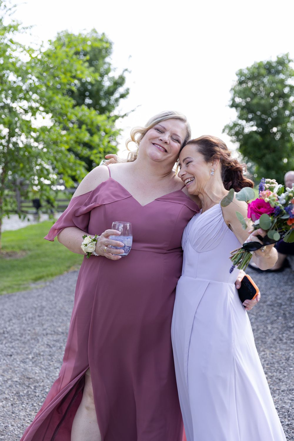 Bridesmaid in mauve dresses, both smiling outdoors at wedding celebration at barn swallow fields in guelph, ontario.