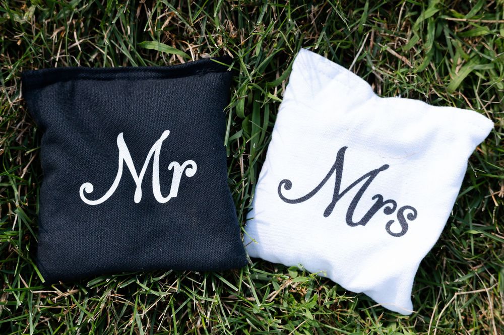 Black & white Mr and Mrs embroidered cornhole bags on green grass, perfect for wedding lawn games at barn swallow fields in guelph, ontario