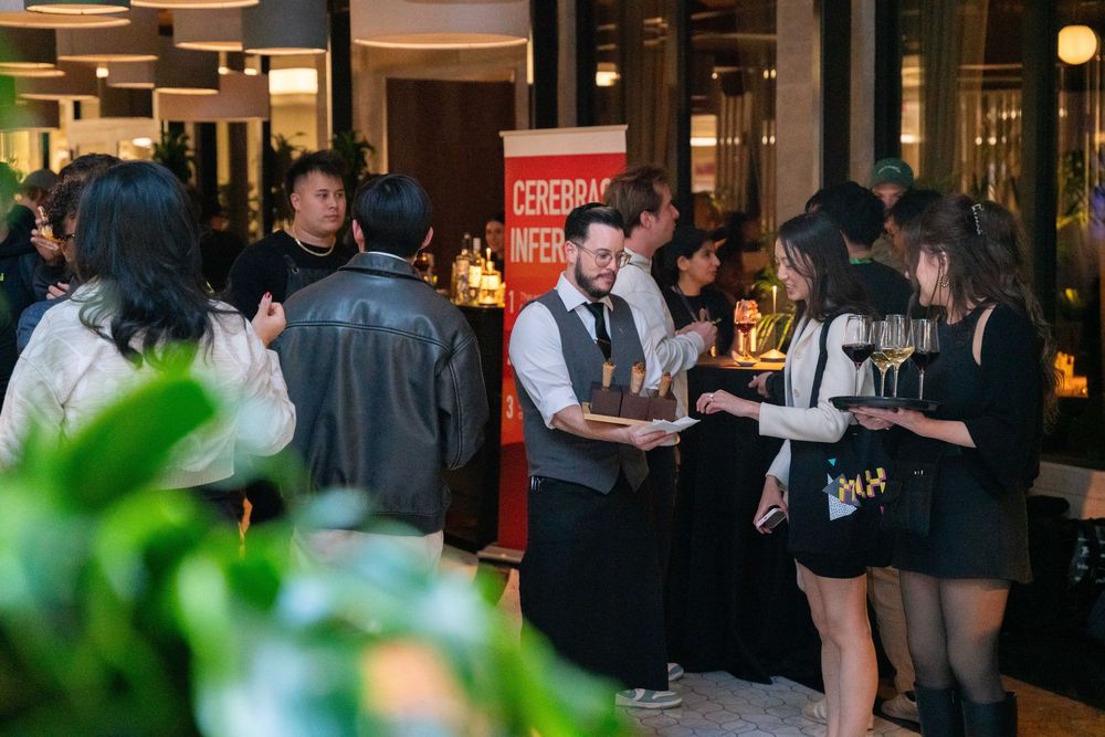 A waiter serves drinks at a busy networking event with guests mingling near a Cerebral beer promotional banner.