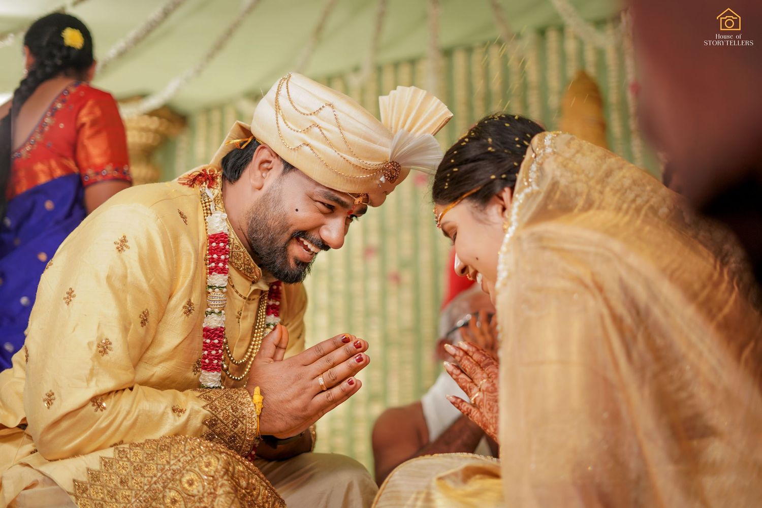 Indian couple in golden wedding attire exchange namaskar gesture during traditional Hindu marriage ceremony.