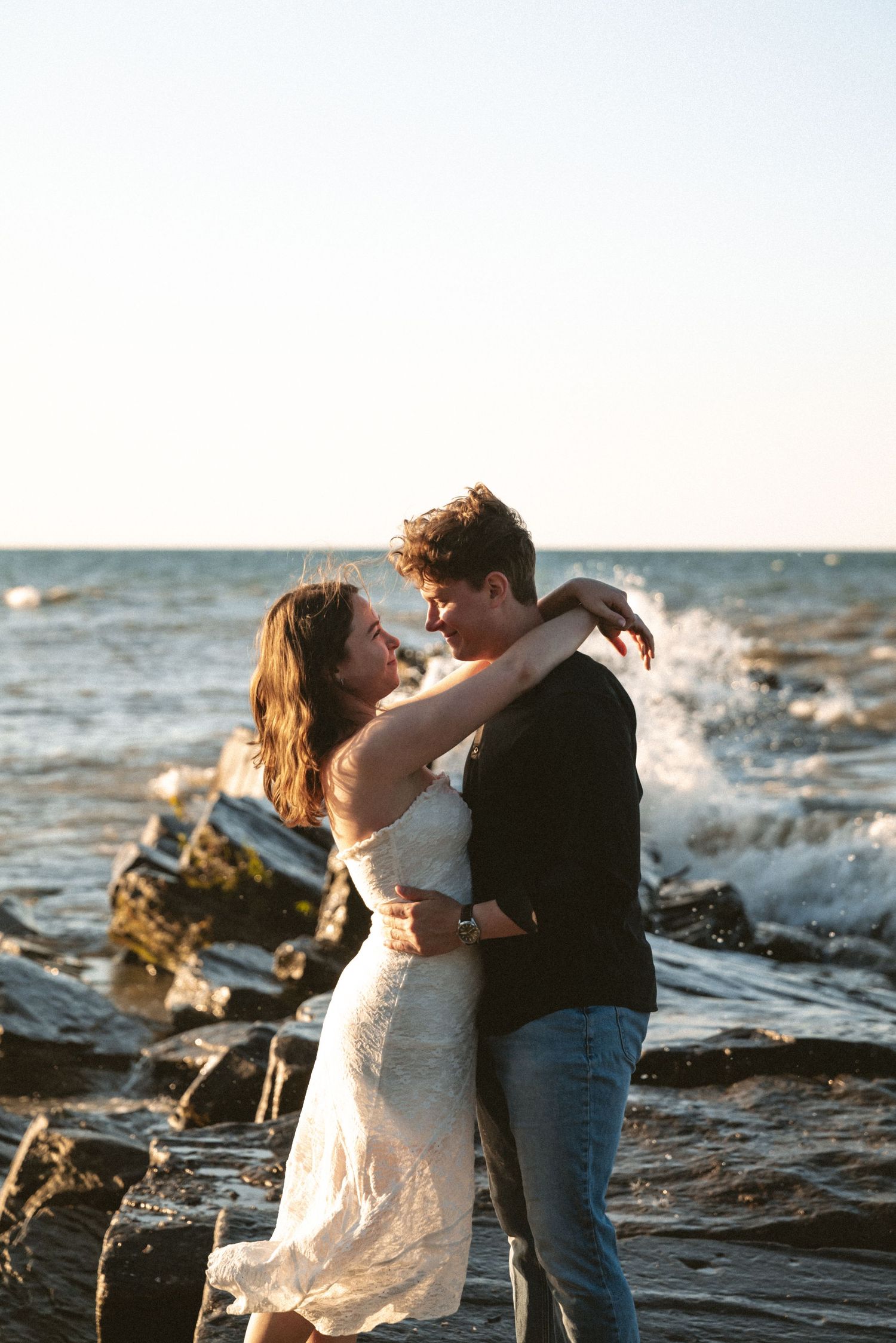 Lush pink and peach floral arrangement decorates the aisle beside white chairs at an outdoor wedding.