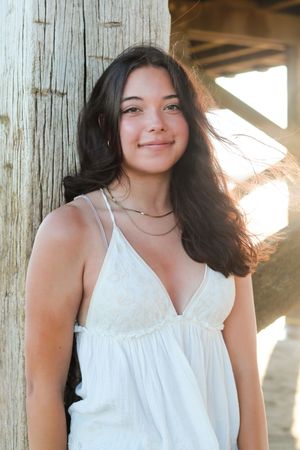 Natural light portraits under wooden beams wearing a white summer top.