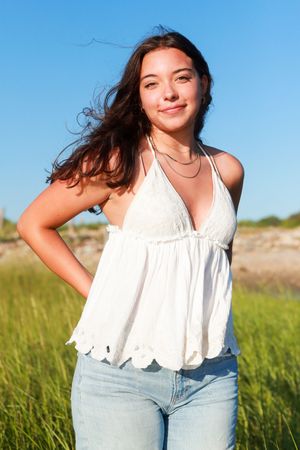 Summer fashion photos in a grassy field wearing light denim and white top.