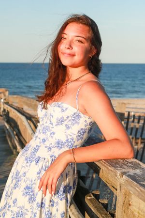 Beachside portraits on a wooden pier wearing a blue floral sundress.
