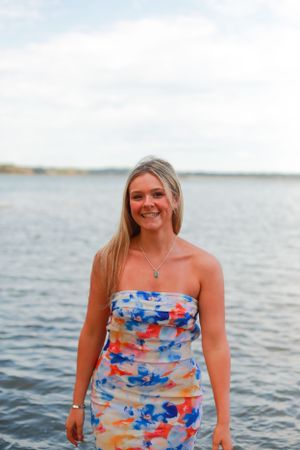 A waterfront portrait featuring someone in a colorful patterned dress with water and sky in background.
