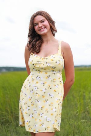 Portrait session in a grassy field wearing a yellow floral summer dress.