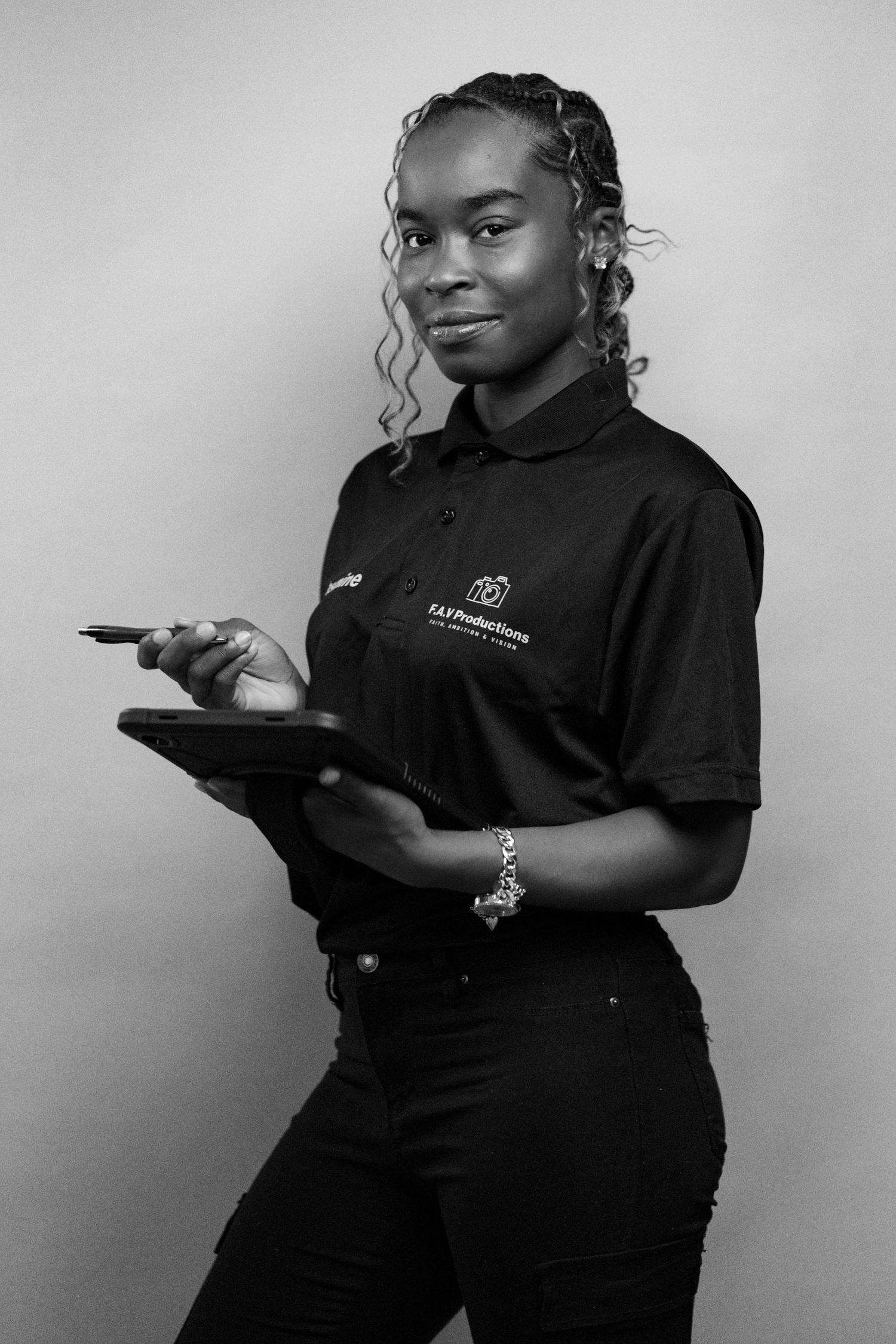 Black and white portrait of a young woman in a black polo shirt holding a tablet and stylus pen.