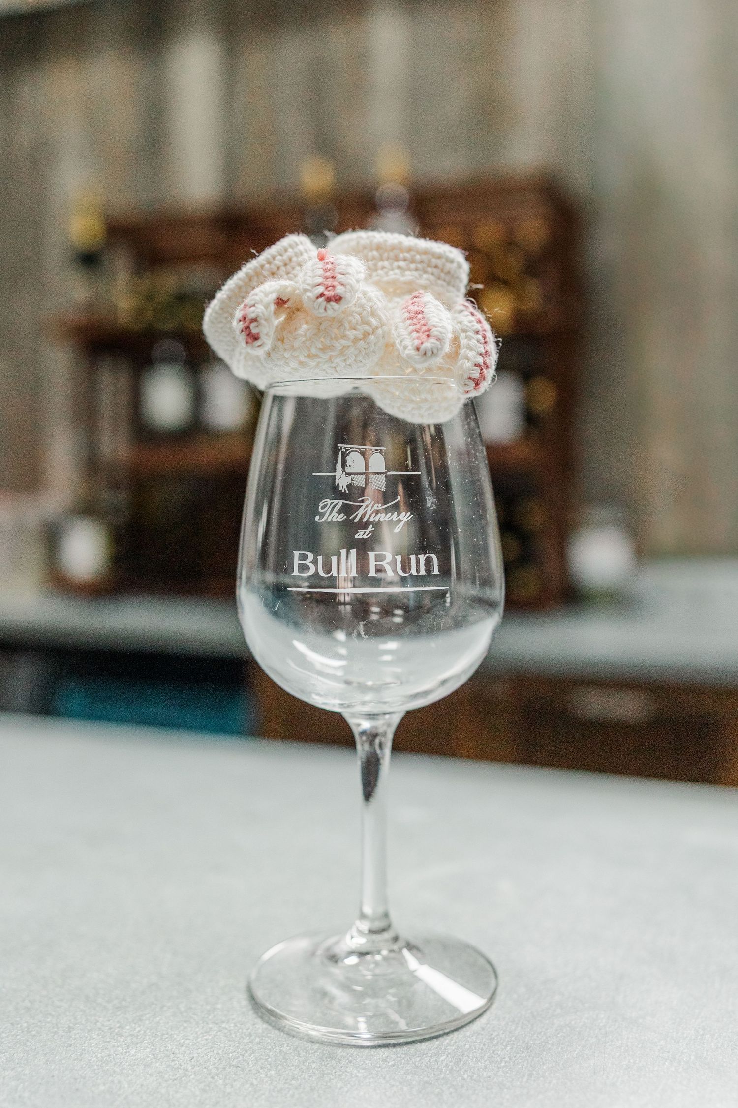 Engraved Bull Run wine glass with miniature knitted baseball booties balanced on the rim.
