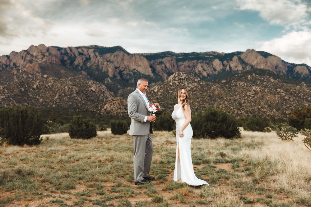 Bride and groom exchange vows outdoors with stunning Sandia Mountains backdrop in New Mexico desert landscape.