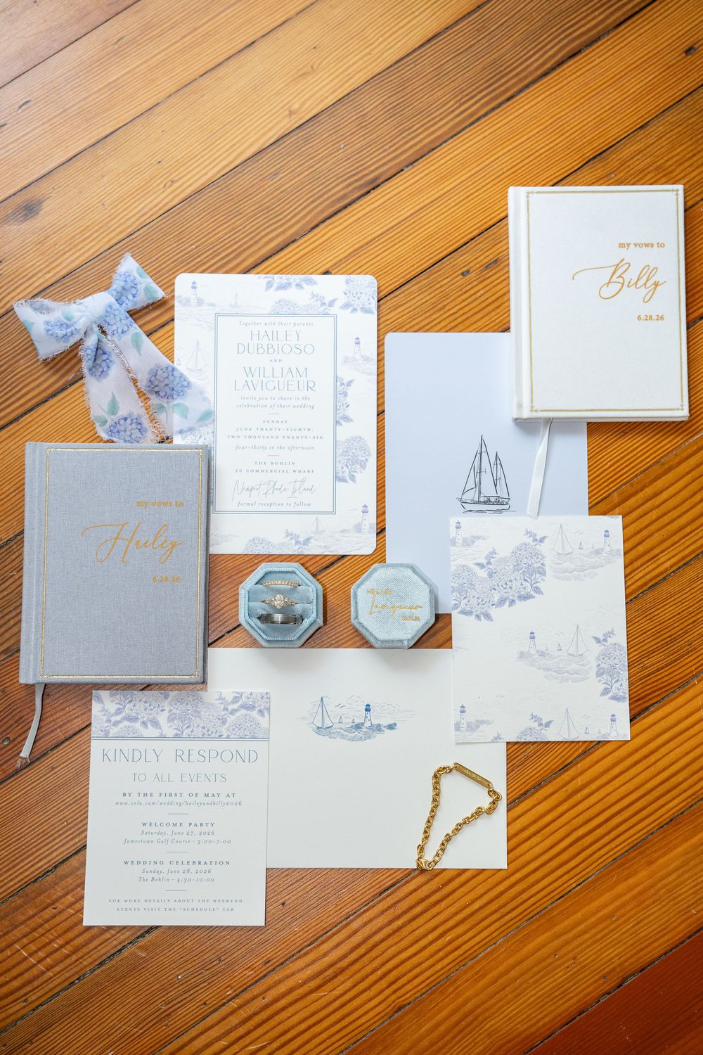 Elegant wedding stationery suite with blue toile invitations, ring box, and gold accents on wood.
