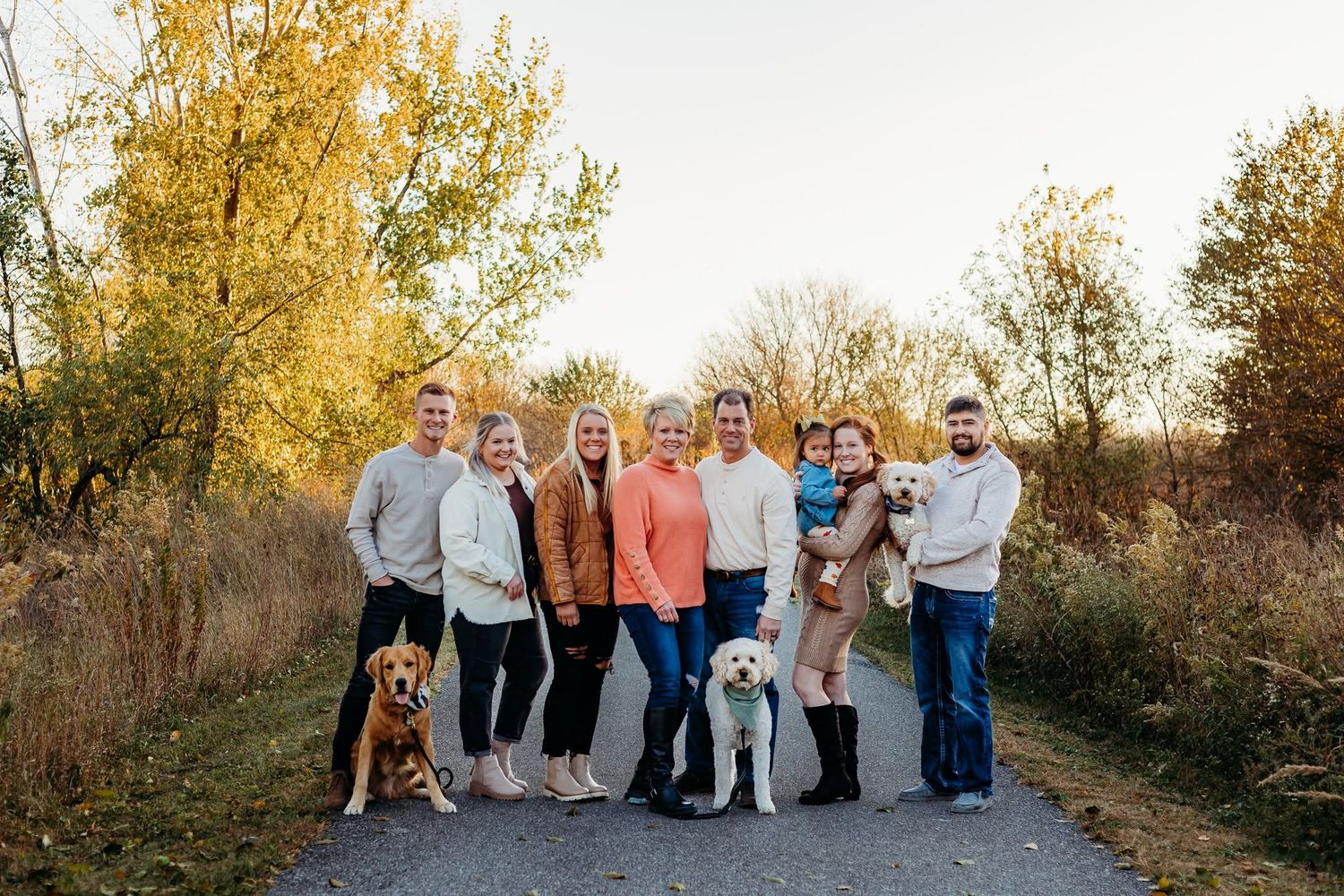 A family of 8 with 3 dog all standing together and smiling for a photo.