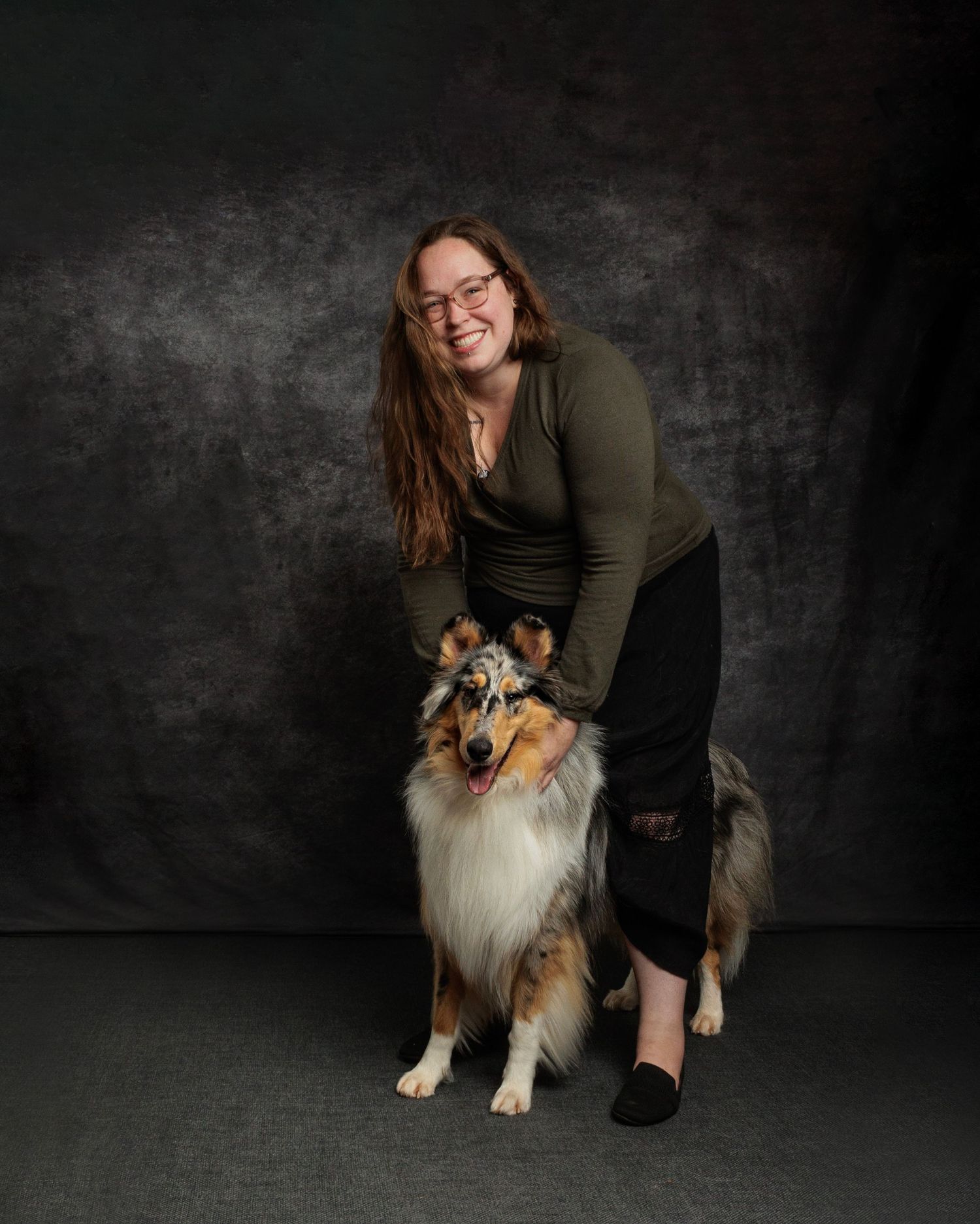 Woman smiling with a tricolor Rough Collie dog posing together in a professional studio portrait setting.