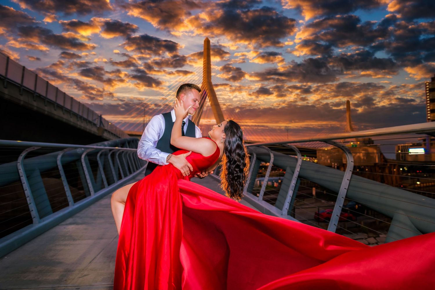 Couple kissing on bridge at sunset with red flowing dress and Eiffel Tower in background.