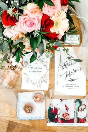 Elegant wedding stationery flat lay with floral bouquet, invitations, and bridal accessories on wood.