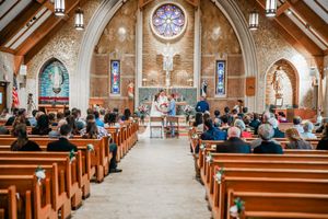 Wedding ceremony inside beautiful stone church with stained glass window and wooden pew seating.