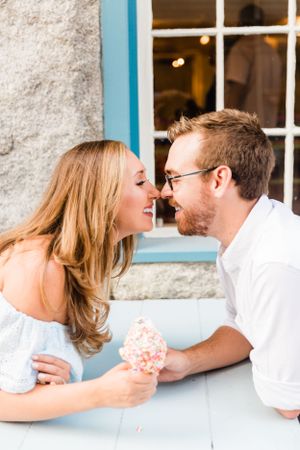 Happy couple shares a romantic moment over a sprinkle ice cream cone at a charming shop.