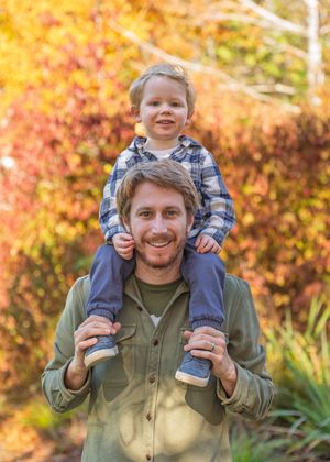 Family photo taken on the Coast of Maine with vibrant autumn foliage and warm fall colors.