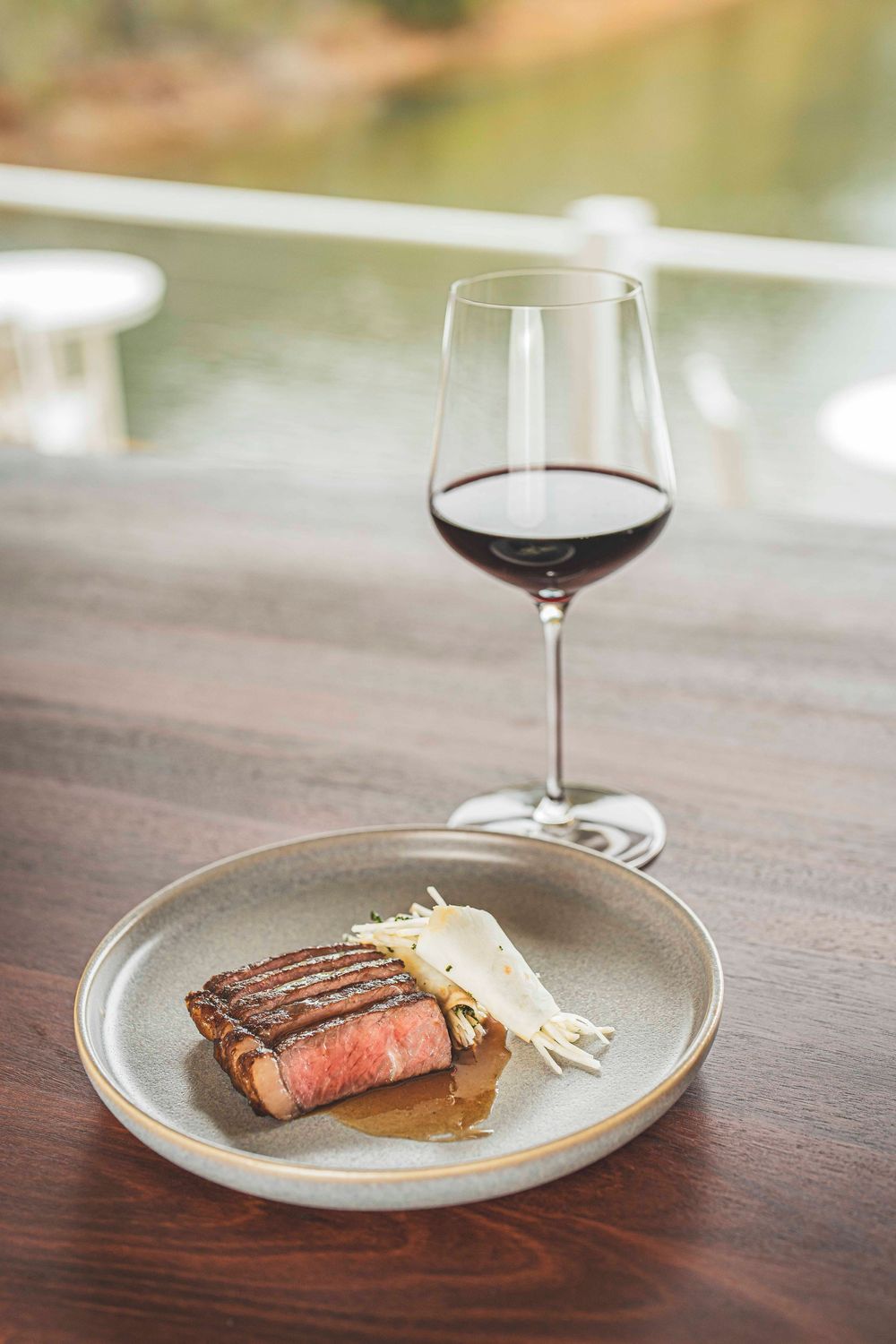 Perfectly seared steak served on a ceramic plate with a glass of red wine at an elegant restaurant.