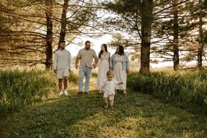 Family of five walking through a sunlit forest clearing on a warm golden afternoon.
