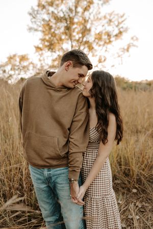 Couple holding hands and sharing a tender moment in a golden field during autumn.