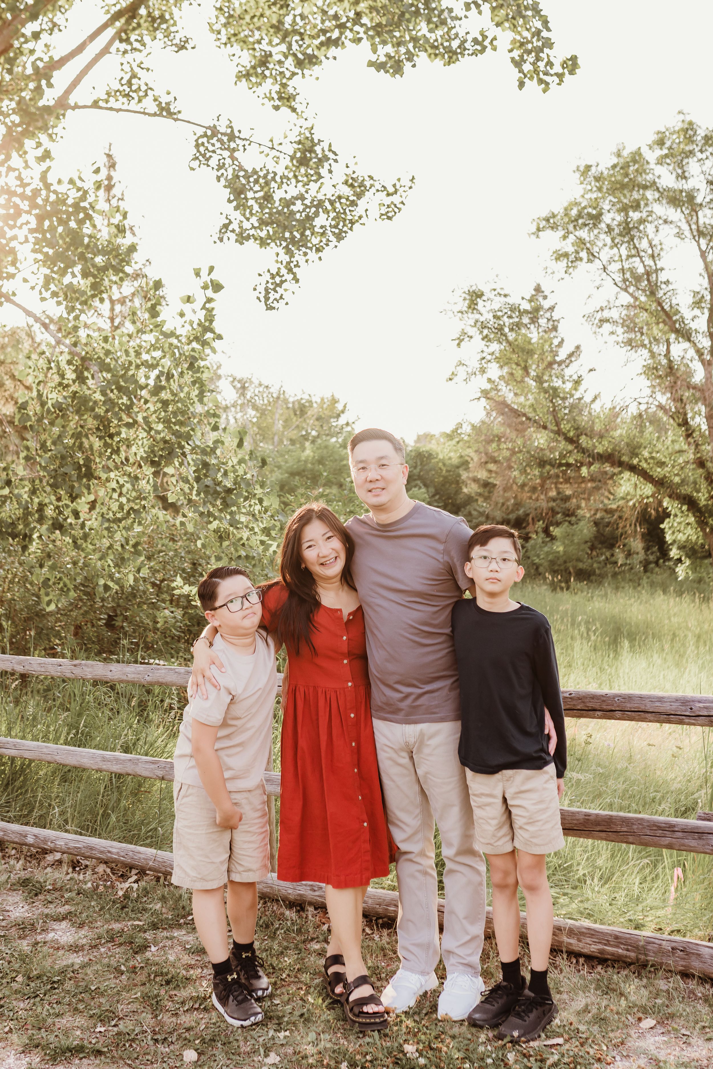 erica standing along a fence with her husband and  sons