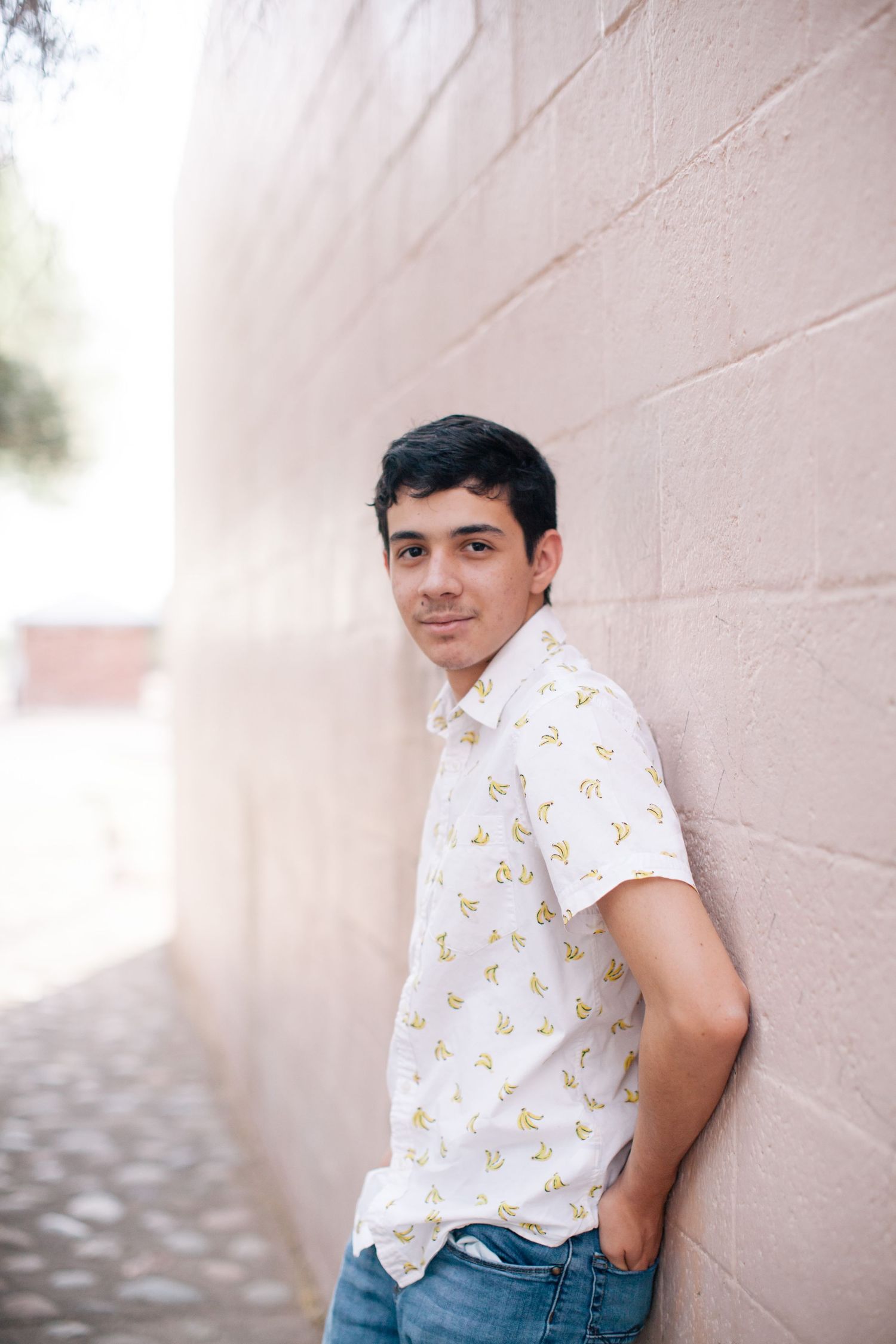 Casual portrait against pink wall wearing patterned short sleeve shirt and jeans.